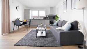 A modern living room with a grey sofa, a coffee table, and a dining area with a table and chairs. - Deluxe apartment in the centre of OS (Osnabrueck)