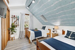 Un dormitorio acogedor con techo inclinado, mobiliario de madera y decoración náutica.