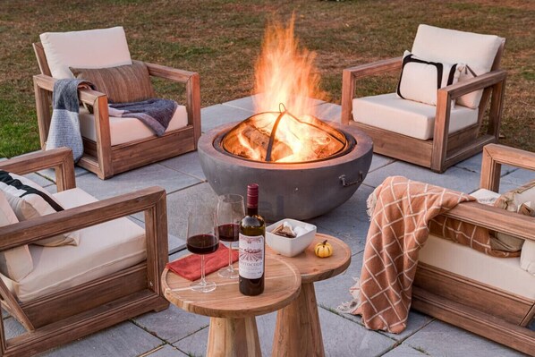 Un hogar rodeado de mobiliario de madera, incluyendo sillas y una mesa con copas de vino y una botella.
