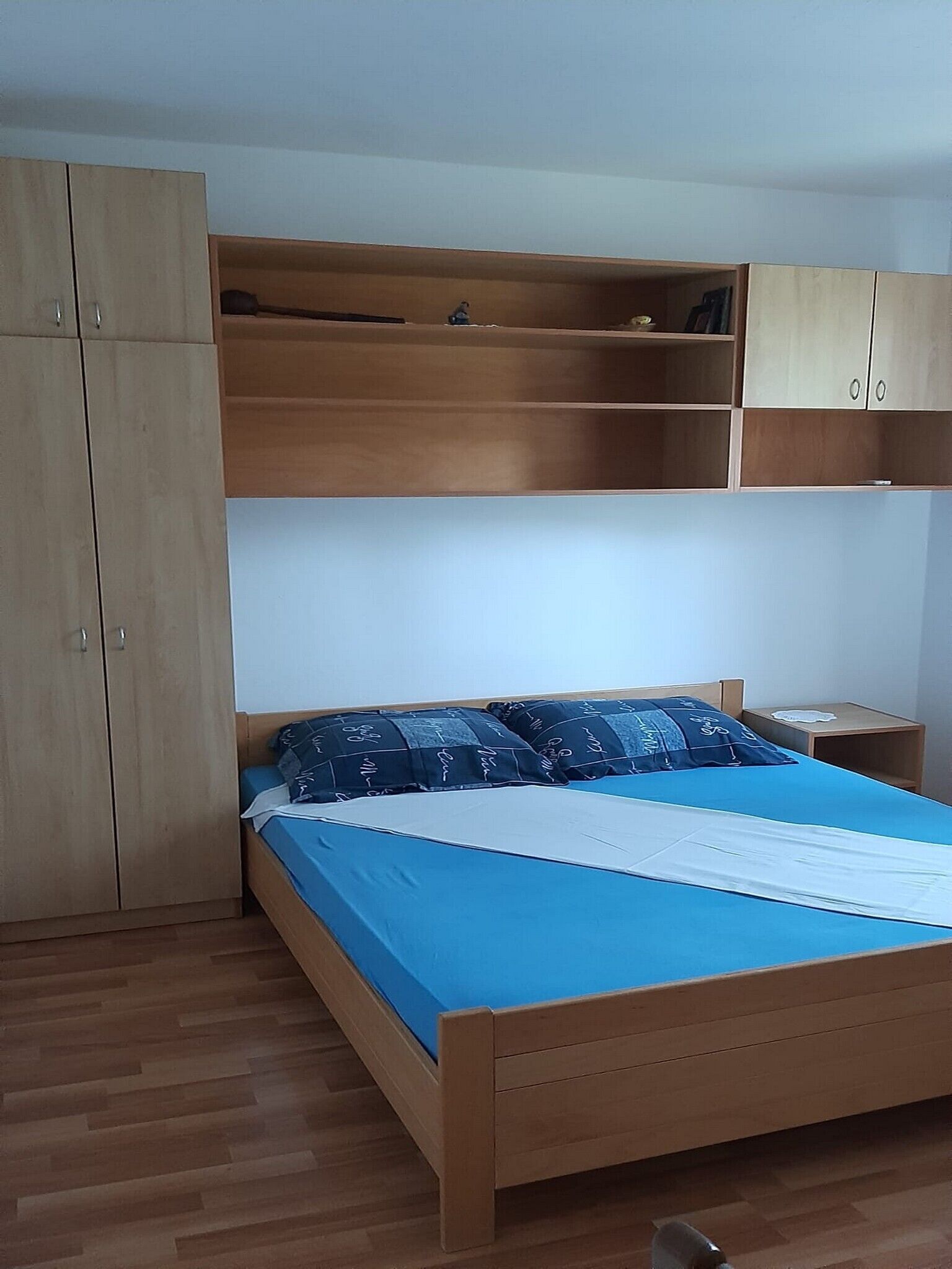 Un dormitorio con cama, armario de madera y estanterías empotradas.