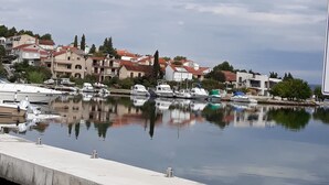 Un port de plaisance avec des bateaux amarrés, une promenade en bord de mer et des immeubles résidentiels en arrière-plan.