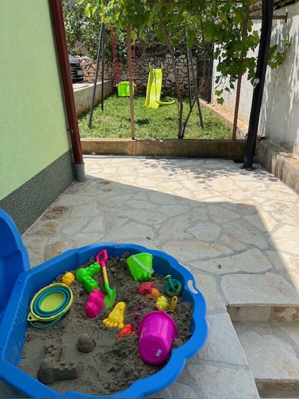 A blue sandbox with various toys and a small tree in the background.