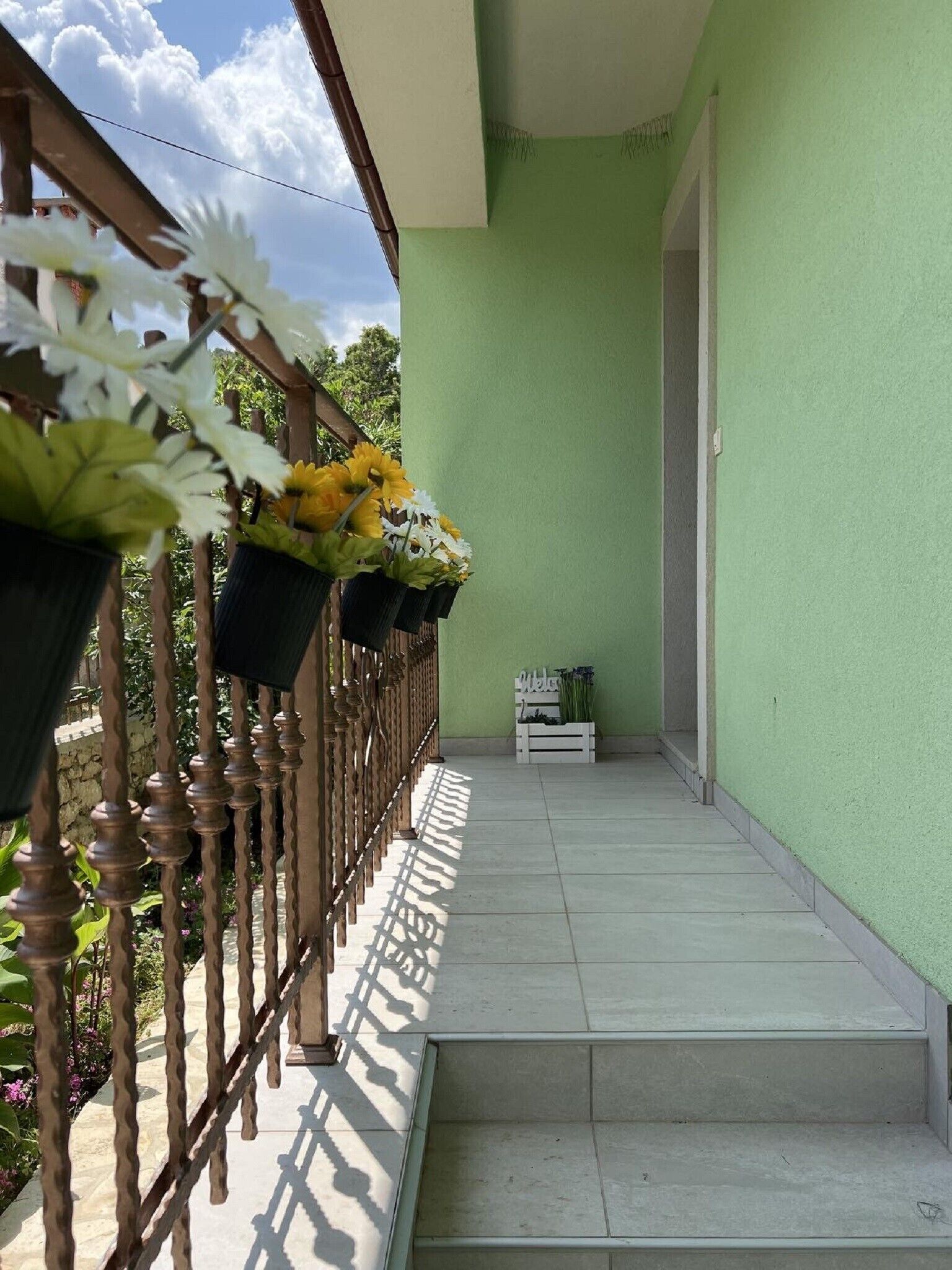 Un balcon agrémenté d’un mur végétal, d’une balustrade en bois et de plantes en pot.