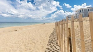 Ein Strand mit einer Holzlattenveranda und einem Gebäude im Hintergrund.