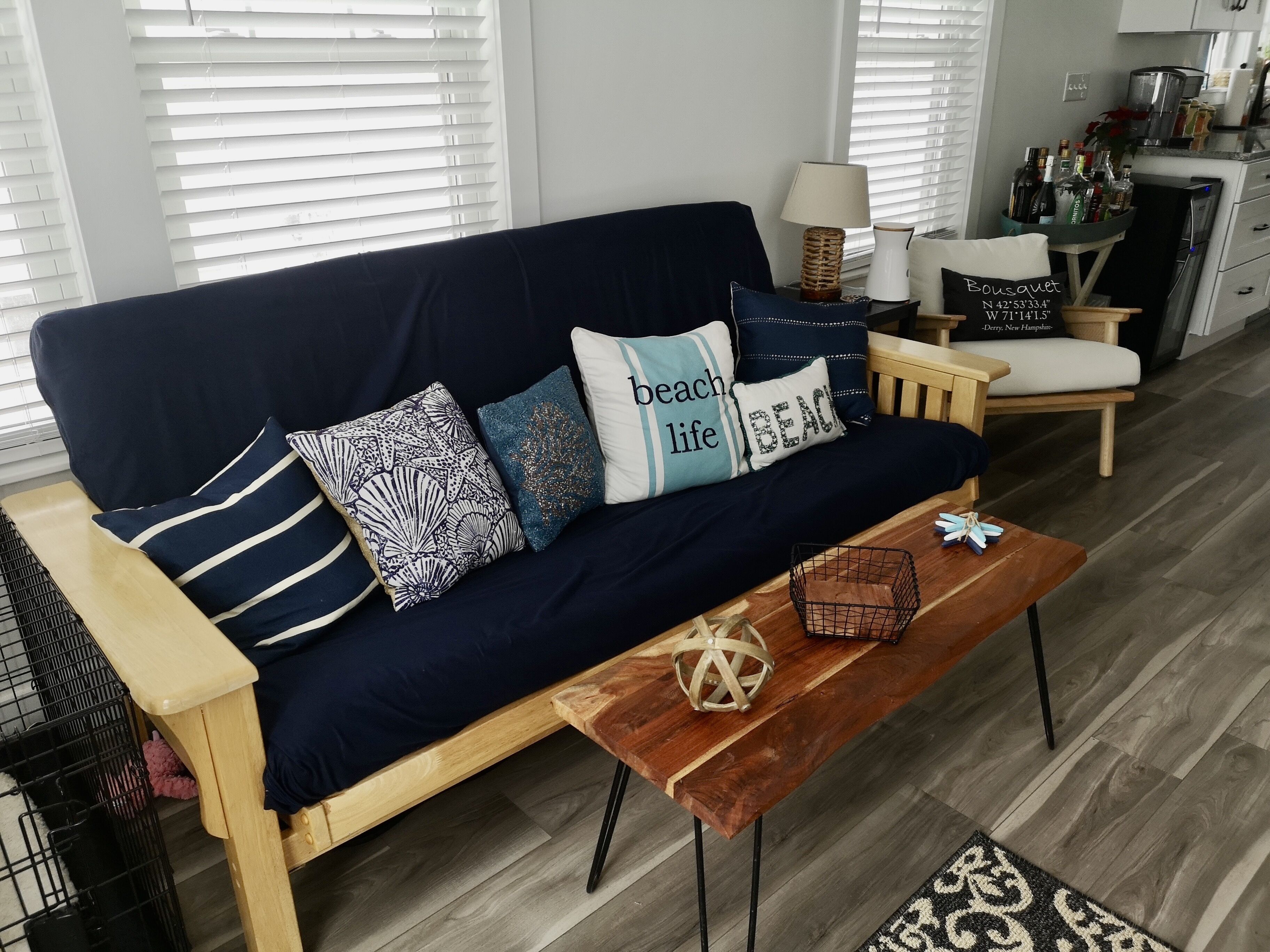 Een moderne woonkamer met een donkerblauwe bank, gestreepte kussens en een houten salontafel.