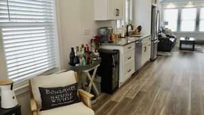Eine moderne Küche mit weißen Schränken, ein Essbereich mit einer schwarzen Ledersofa und ein Holzboden.