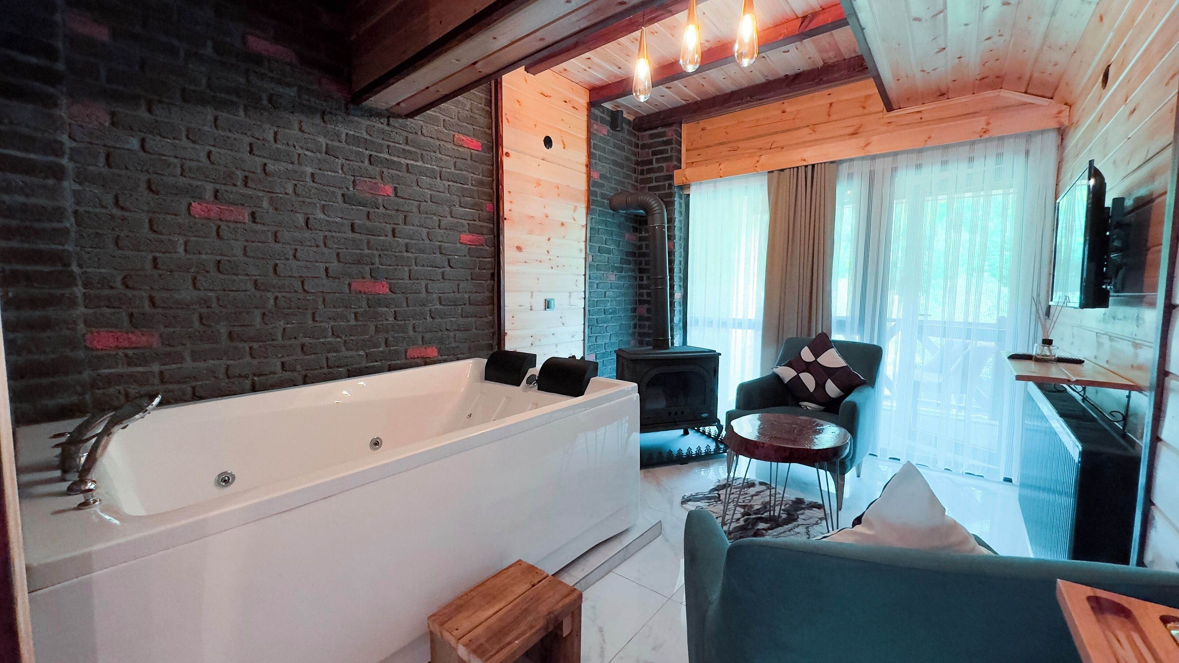 A modern bathroom with a large bathtub, a wooden bench, and a small table with a chair.