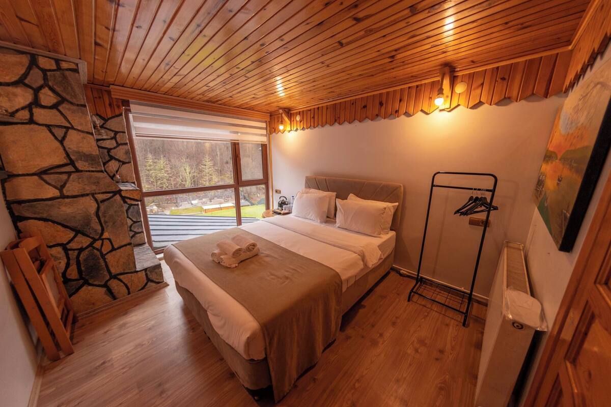 A cozy bedroom with a stone wall, wooden ceiling, and a bed with a neatly made bedspread.