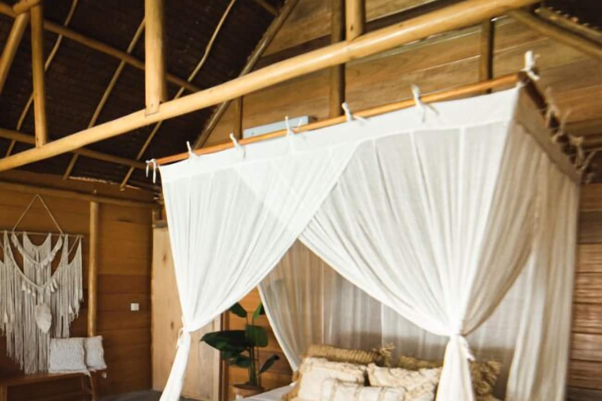 A bed with a canopy, a macrame wall hanging, and a wooden floor.