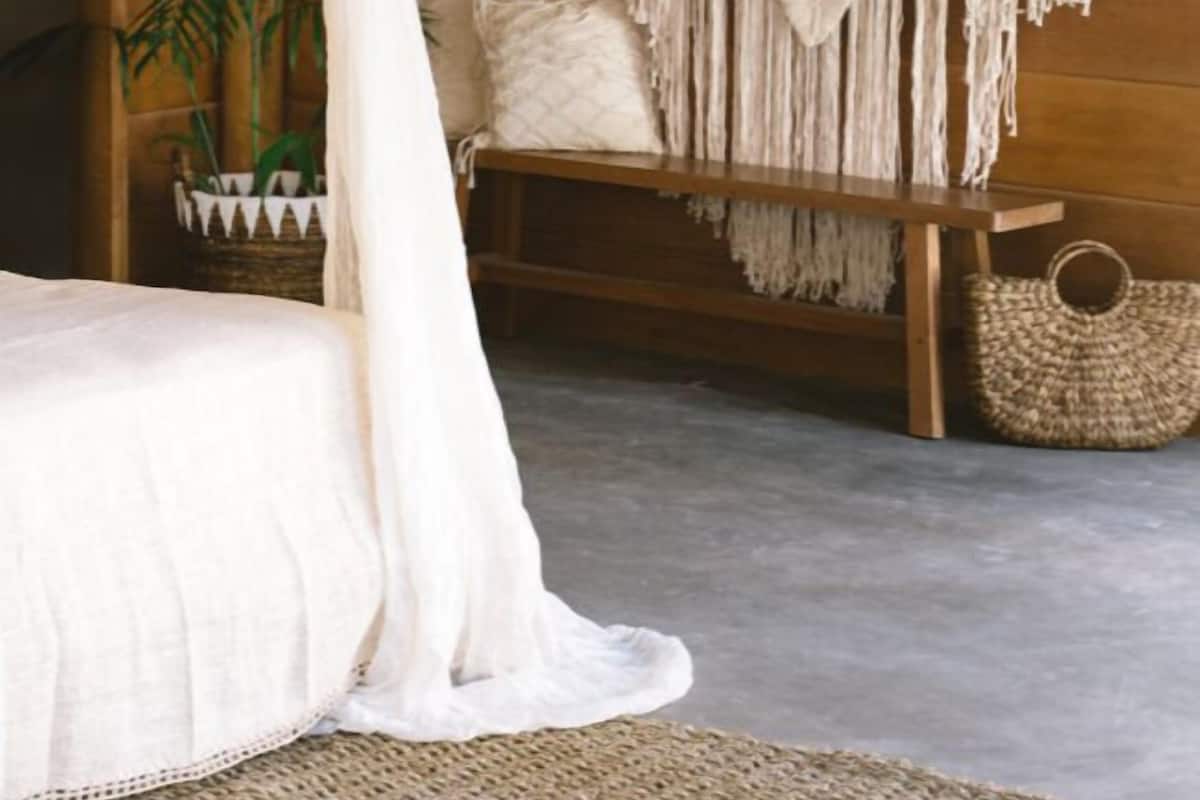 A bedroom with a bed, a macrame wall hanging, and a woven basket.