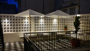 A terrace with a checkered floor, white umbrellas, and a lattice fence. - Maison Victoire (Pointe-à-Pitre)