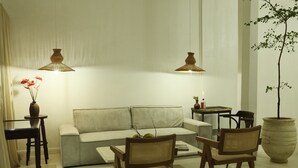 A modern living room with a sofa, two chairs, a coffee table, and two hanging lamps. - Maison Victoire (Pointe-à-Pitre)