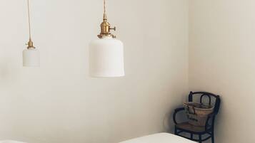 A minimalist bedroom with a bed, two hanging lamps, and a chair.