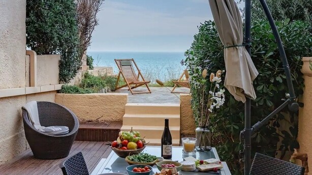 A table set for breakfast with a view of the sea, wicker chairs, and a bottle of wine. - T2 Large terrace with sea view & direct access to the beach – Collioure sector (Port-Vendres)