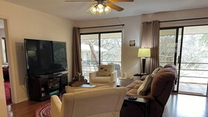 Una sala de estar con televisor de pantalla plana, un sofá, una silla y una mesa de comedor.