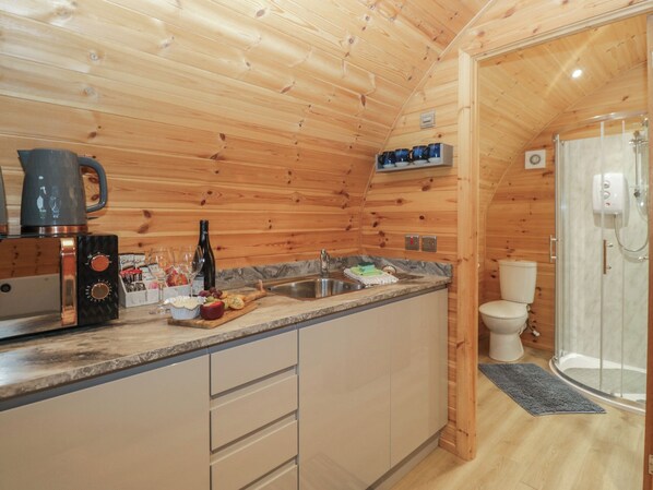 A compact kitchen with wooden walls, a sink, and a coffee maker.