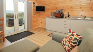 Een gezellig chaletinterieur met houten inrichting, een bank, een televisie en een keukenhoek.