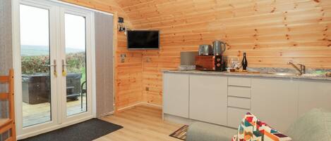 Een gezellig chaletinterieur met houten inrichting, een bank, een televisie en een keukenhoek.