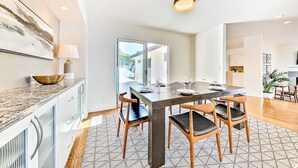 Une cuisine moderne avec une table à manger, des chaises et une grande fenêtre.