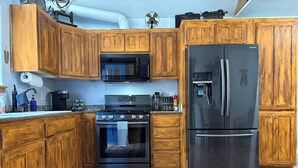 A kitchen with wooden cabinets, a stainless steel refrigerator, a microwave, and an oven.