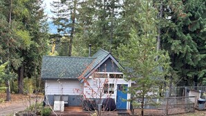 A cabin with a wooden deck, surrounded by dense forest.
