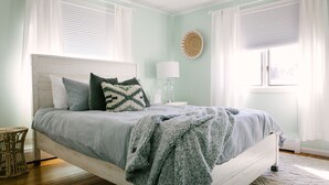 A bedroom with a bed, a nightstand, a lamp, and a window with curtains. - Short Walk to Cape Ann's Best Beaches! (Gloucester)