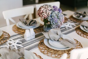A dining table set with plates, napkins, and a centerpiece of flowers. - Short Walk to Cape Ann's Best Beaches! (Gloucester)