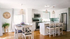 A modern kitchen with white cabinetry, a central island, and pendant lighting. - Short Walk to Cape Ann's Best Beaches! (Gloucester)