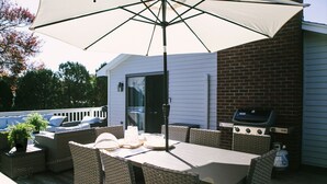 An outdoor patio with wicker furniture, a table, and an umbrella. - Short Walk to Cape Ann's Best Beaches! (Gloucester)