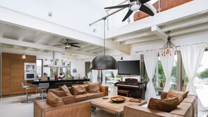 A spacious living area with a modern kitchen, a large ceiling fan, and a flat-screen TV. - Villa Olympia - a palm trees paradise in front of the sea. (Heraklion Crete)