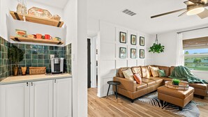Uma sala de estar moderna com um sofá seccional, uma mesa de centro e um espaço de jantar com bancada de cozinha.