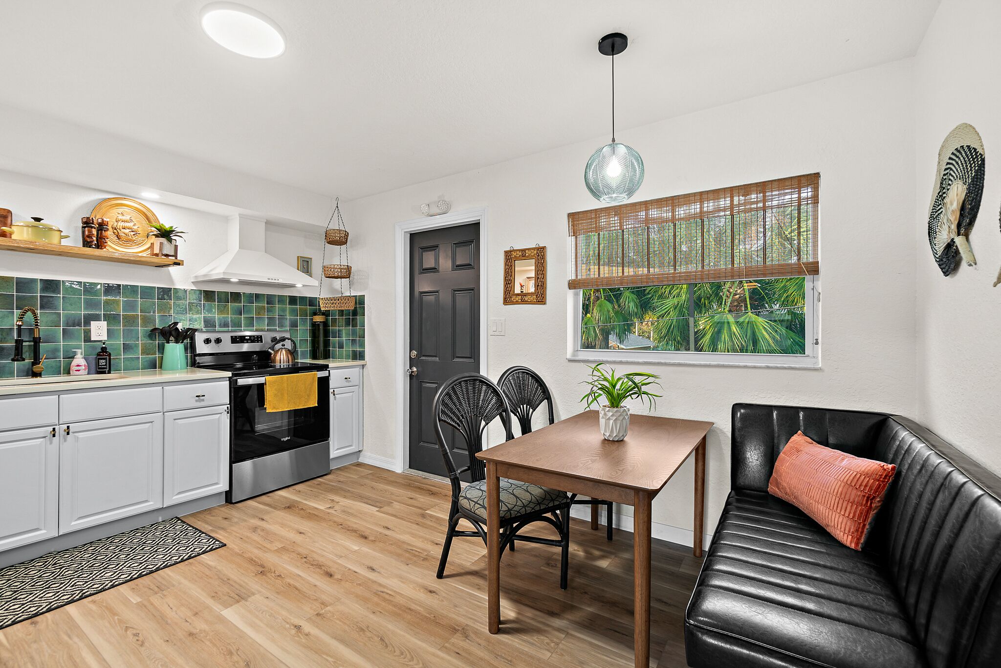 A compact kitchen with white cabinets, a black stove, and a wooden dining table with chairs.
