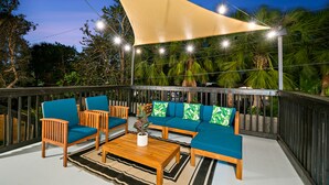 Un área de estar al aire libre con sofá, sillas y una mesa de centro, bajo una pérgola.