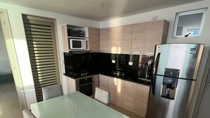 Une cuisine moderne avec une table à manger en verre, des appareils électroménagers en acier inoxydable et des meubles de rangement en bois clair.
