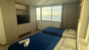 Une chambre d’hôtel avec deux lits, une télévision et vue sur la mer.