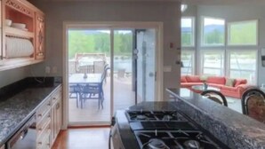 Een keuken met een gasfornuis, houten kasten en een schuifdeur naar een patio met tuinmeubilair.