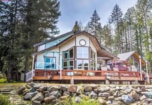 Une cabane dotée d’une grande terrasse, entourée d’arbres.