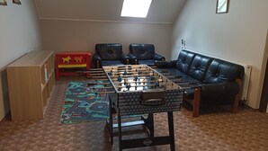 Ein gemütliches Wohnzimmer mit einem Tischfußballspiel, einer Couch und einer roten Spielküche.