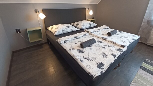 Ein Doppelbett mit floraler Bettwäsche, Nachttische und Wandlampen.