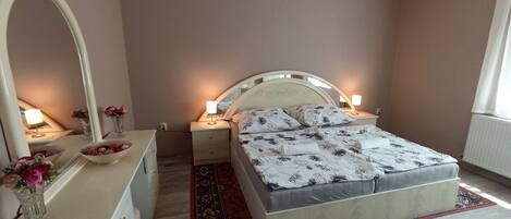 Une chambre à coucher avec un lit, des tables de chevet, un miroir et une commode.