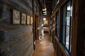 Stunning hallway with artwork and windows, leading to a cozy bedroom with a checkered floor and a comfortable bed.
