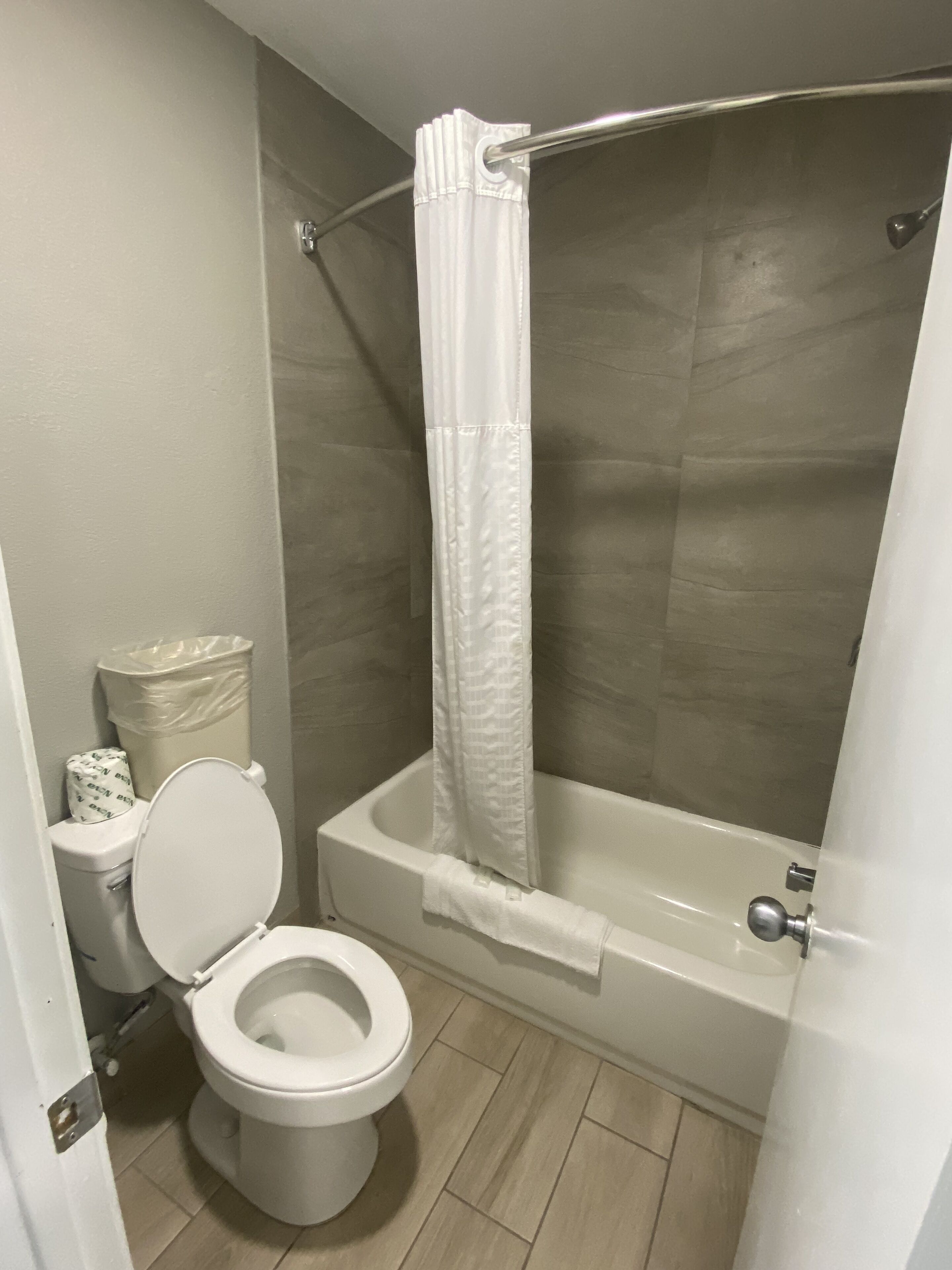 A bathroom with a toilet, a bathtub, and a shower curtain.