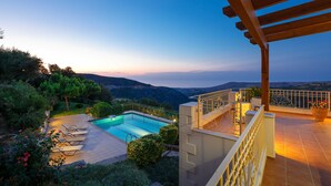 Ein Pool auf dem Dach mit Blick auf die Berge, eine überdachte Terrasse mit Sitzgelegenheiten und ein gepflegter Garten.