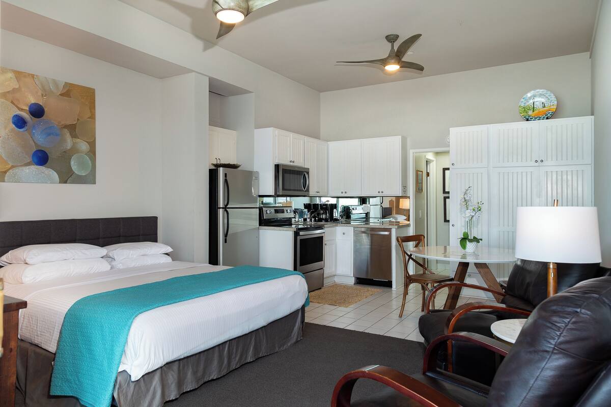Una habitación de hotel moderna con cama, escritorio, kitchenette y zona de comedor.