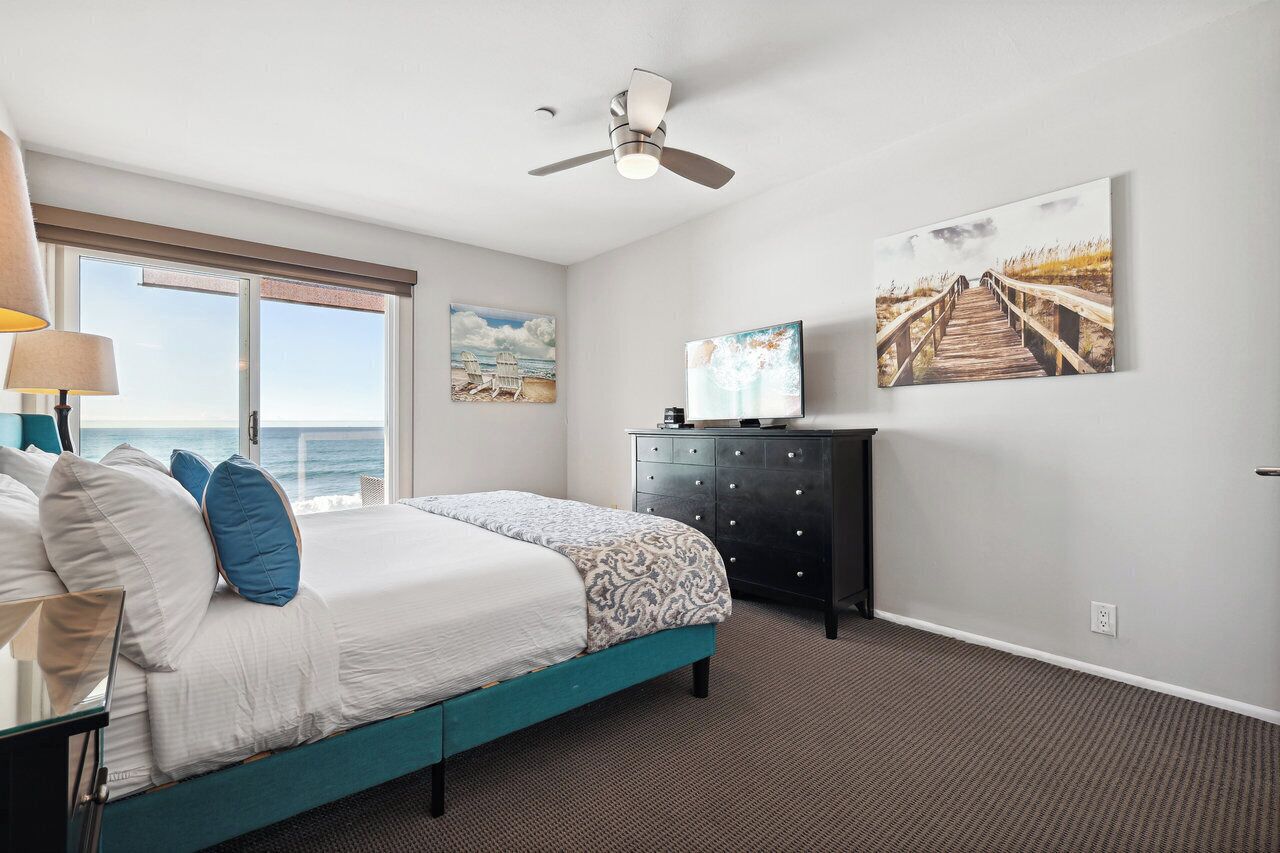 A bedroom with a bed, a dresser, a TV, and artwork on the wall.