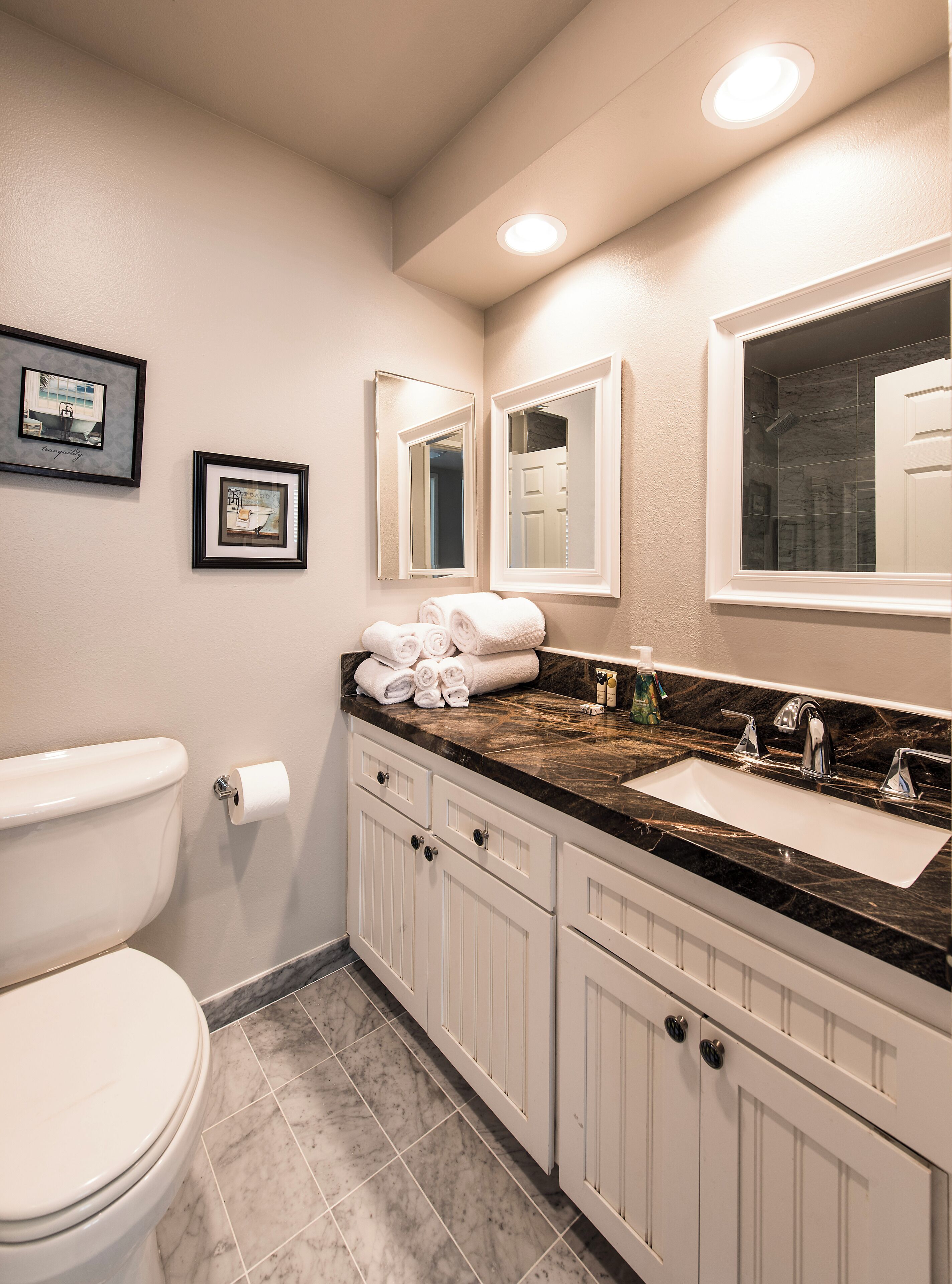 A bathroom with a toilet, sink, and mirror.