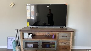 A wooden entertainment center with a flat-screen TV, drawers, and shelves.