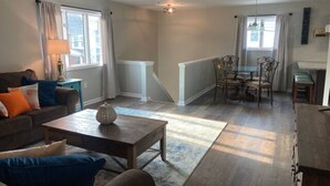 A spacious living room with a sofa, coffee table, and dining area with chairs.