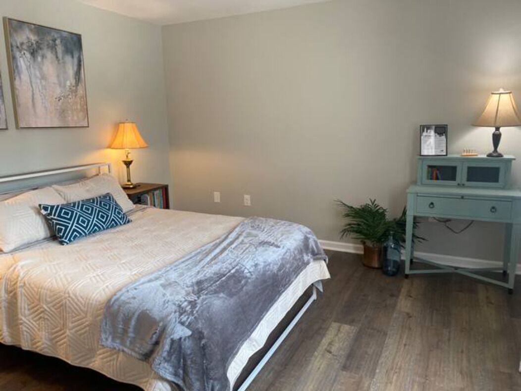 Une chambre à coucher avec un lit, des tables de chevet, un bureau et une lampe.