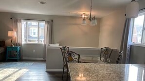 A dining area with a granite table, chairs, and a chandelier.